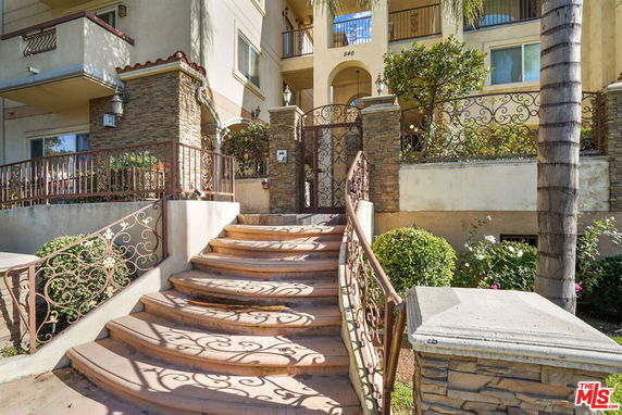 Front view of a multi-story residential building with stone accents and a curved staircase leading to the entrance.