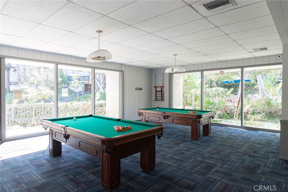 Room with two billiard tables and large windows.
