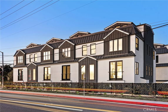 Front view of a modern multi-story building with large windows and a pitched roof.
