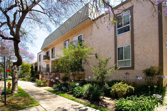 Front view of a two-story residential building with a manicured garden and pathway.