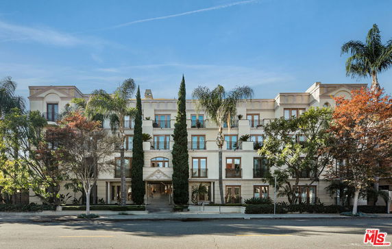Front view of a multi-story building with ornamental trees and shrubs.