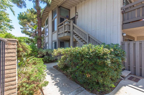 Front view of a two-story building with outdoor stairs and surrounding greenery.