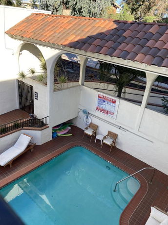 Outdoor area with a small swimming pool surrounded by lounge chairs and a tiled patio.