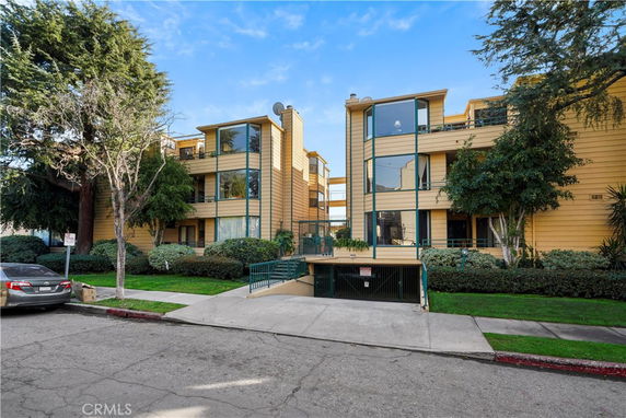 Front view of a multi-story apartment building with large windows and beige exterior.