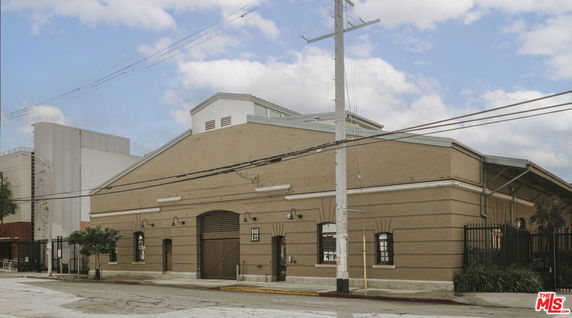 Front view of a beige brick building with an arched entrance and a sloped roof.