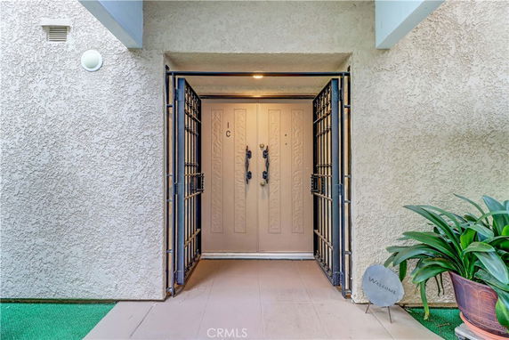 Entrance of a building with a light-colored textured wall and a double door.