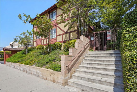 Front view of a two-story house with a gated entrance and stairs.