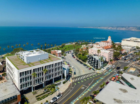 Aerial view of a coastal area with buildings and a road close to the ocean.