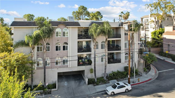 Front view of a multi-story apartment building with palm trees.
