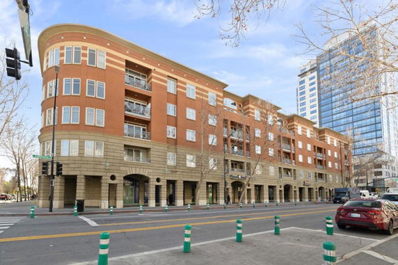 Front view of a multi-story building with balconies on an urban street corner.