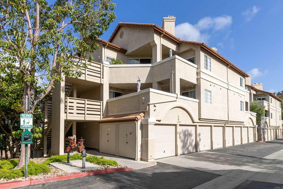 Front view of a multi-story apartment building with garages on the ground level.