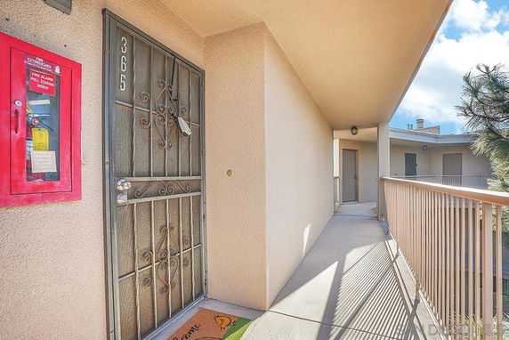 Exterior view of an apartment entrance with a metal door and railing.