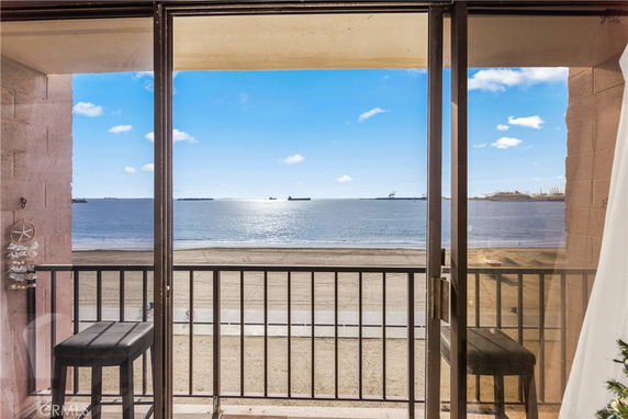 View of beach and ocean from a balcony with ships in the distance.