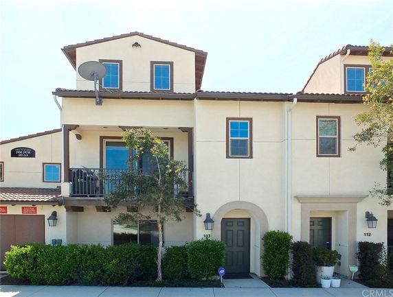 Front view of a multi-story building with balconies and a satellite dish.