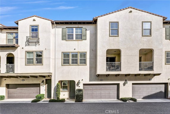 Front view of a multi-story townhouse with garages and balconies.