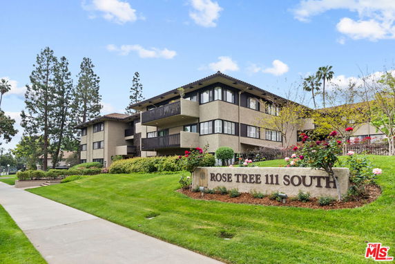 Front view of a multi-story residential building with balconies and landscaped garden.