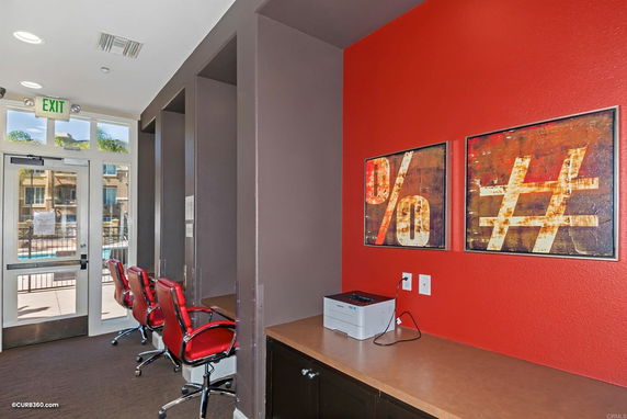 Interior view of a clubhouse area with red chairs and modern artwork on the wall.
