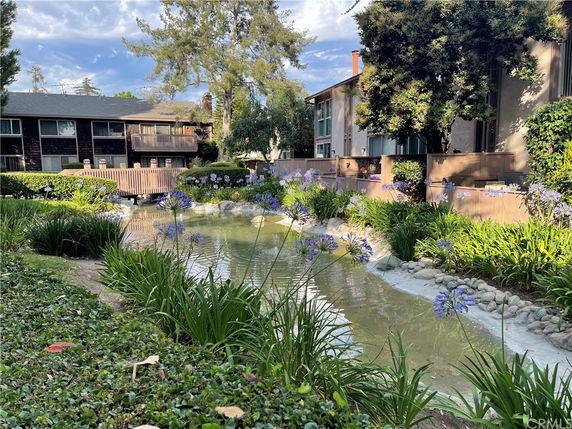 View of a residential complex with a pond and lush greenery.