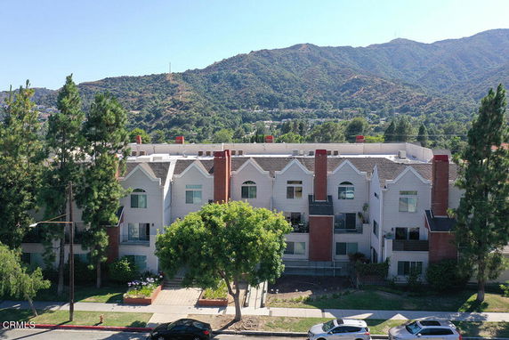 Front view of a multi-story building with chimneys and a mountain backdrop.