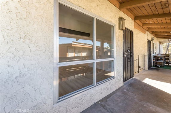Front view of a house with a large window and secured door on a covered porch.