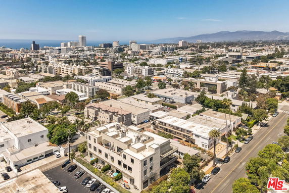 Aerial view of a cityscape with multiple buildings and a distant ocean view.