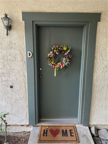 Front view of a door with a wreath and doormat.