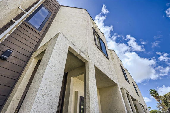 Front view of a modern multi-story building with textured walls and large windows.