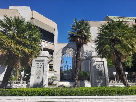 Front view of a building with a gated entrance and palm trees.