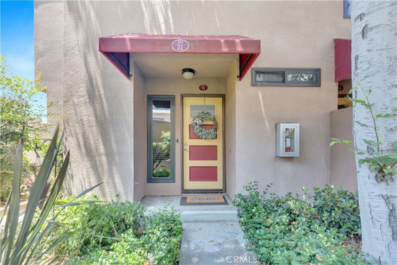 Front view of a modern house entrance with a red awning and a wreath on the door.
