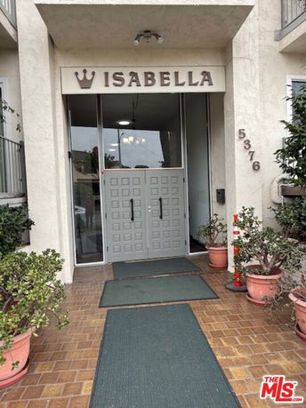 Front entrance of a building named Isabella with double doors and potted plants.