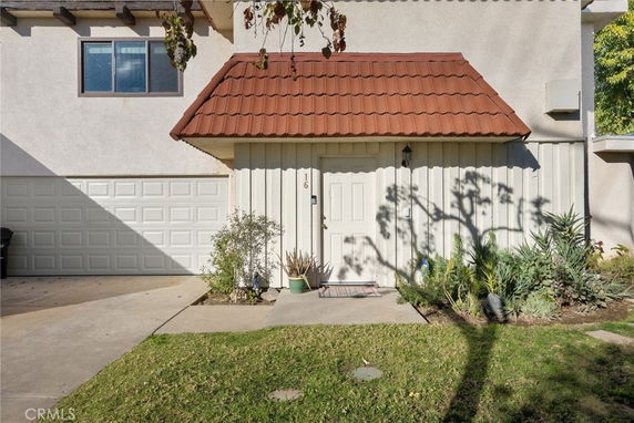 Front view of a house with a garage and red tiled roof over entrance.