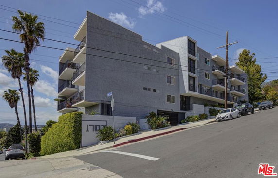 Front view of a multi-story building on a sloped street.