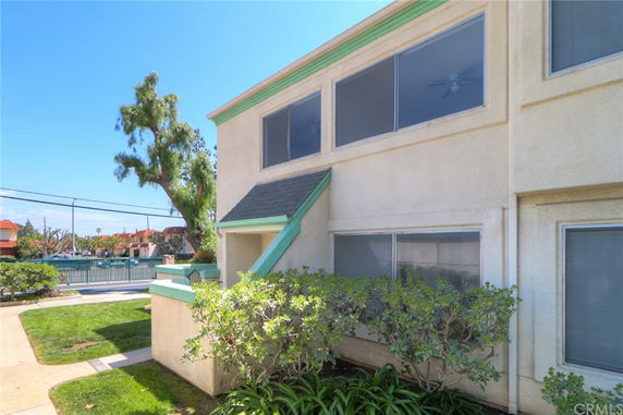 Front view of a two-story building with large windows and trimmed bushes in front.