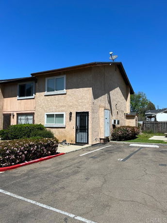 Front view of a two-story building with beige stucco and a satellite dish on the roof.