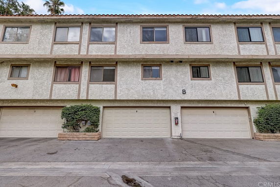Front view of a three-story residential building with multiple garage doors on the ground level.