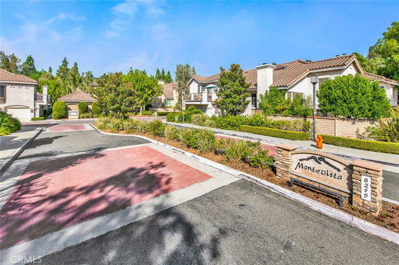Front view of residential buildings in a neighborhood with landscaping and paved road.
