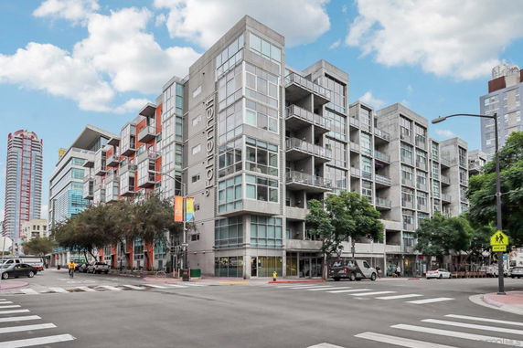 Front view of a modern multi-story apartment building with large windows and balconies.