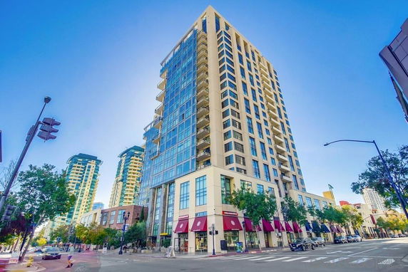Front view of a tall multi-story building with glass windows and balconies.