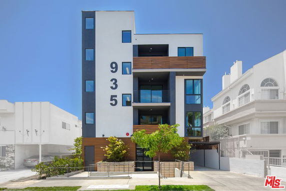 Front view of a multi-story modern apartment building with prominent street numbers '935'.