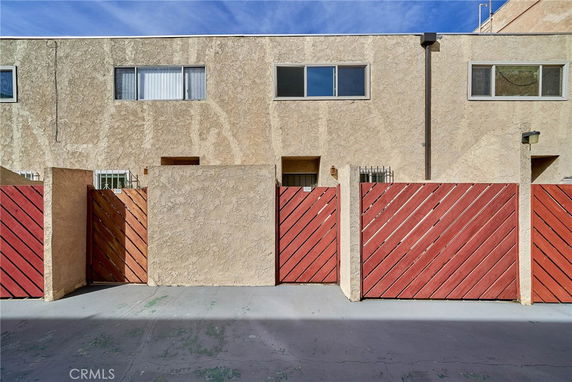 Front view of a building with textured stucco walls and red wooden gates.
