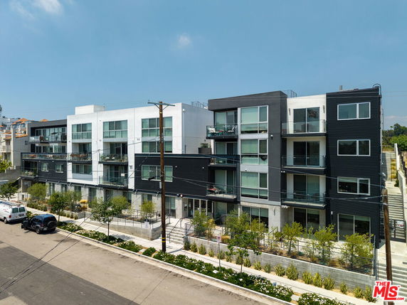 Front view of a modern multi-story apartment building with balconies and large windows.
