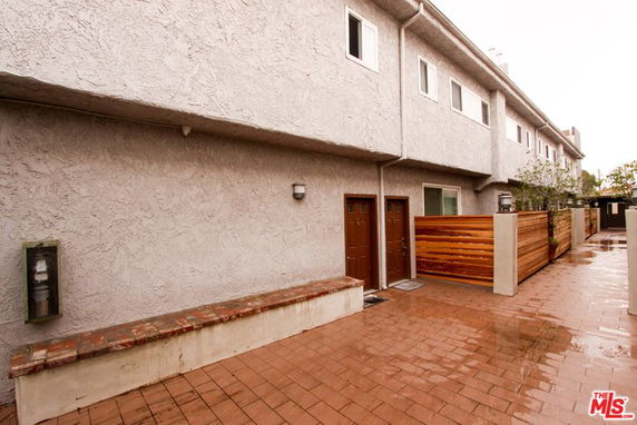 Front view of a multi-level building with brick walkway and wooden fence