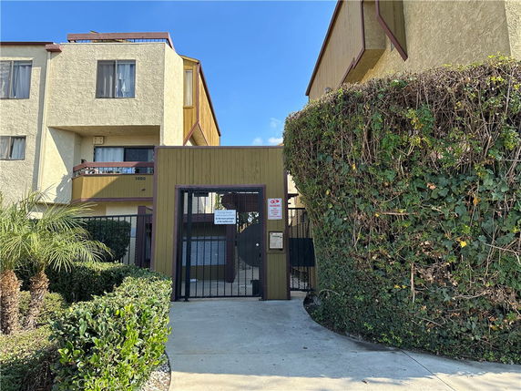 Front view of a multi-story building with balconies and gated entrance.