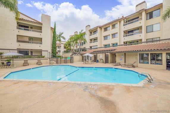 Outdoor swimming pool area with multi-story buildings in the background.