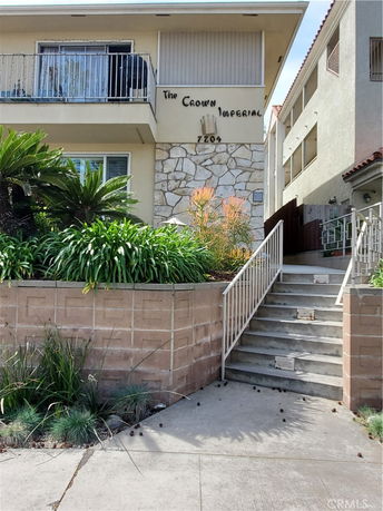 Front view of a multi-story building with a balcony and stair entrance.