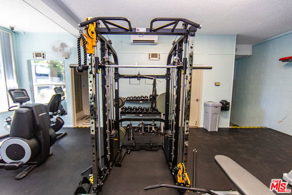 Indoor gym area with exercise equipment and weights.