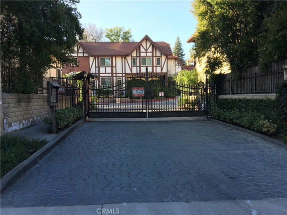 Front view of a house with Tudor-style architecture and a gated driveway.