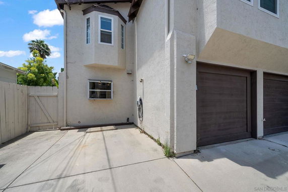 Outdoor parking area next to a house with garages and concrete driveway.