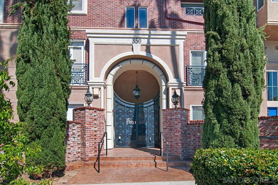 Front view of a multi-story building with an arched entrance and decorative iron gate.