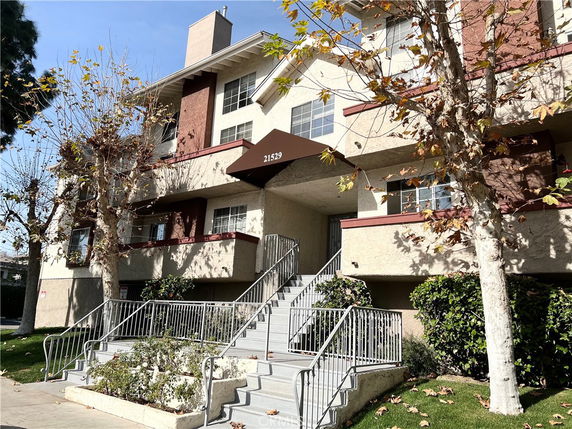 Front view of a multi-story residential building with balconies and stairs.